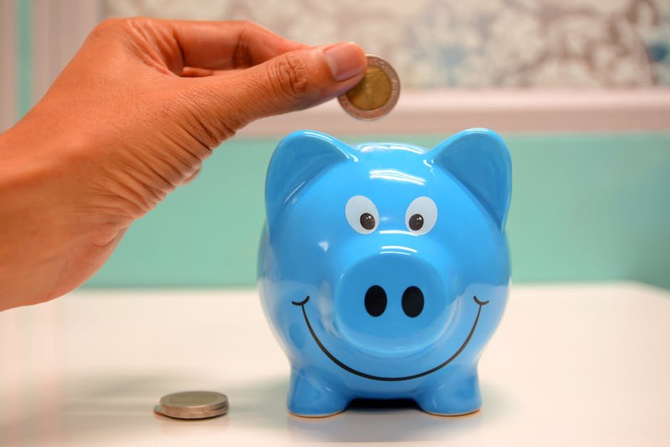 Hand inserting a coin into a blue piggy bank