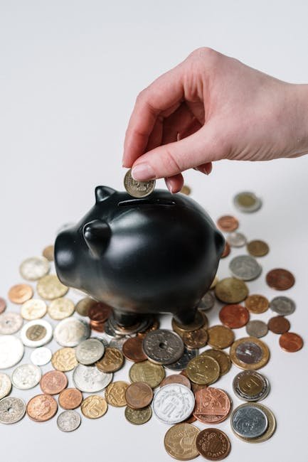 Hand inserting coin into a black piggy bank